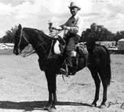 Black and white photo of a man riding a horse